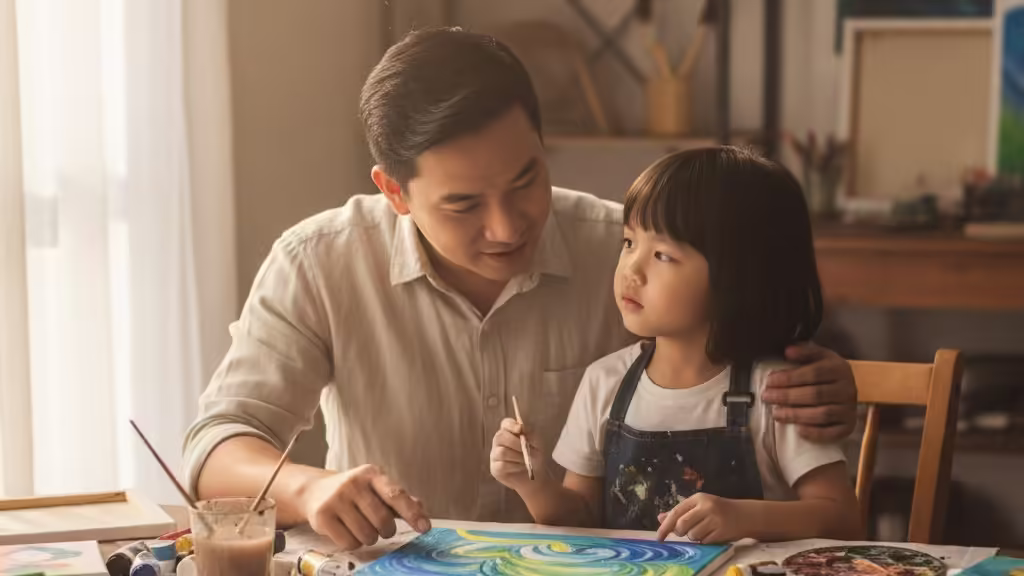 Cha kiên nhẫn hướng dẫn con trai cách kết hợp màu sắc trong tác phẩm nghệ thuật của bé.